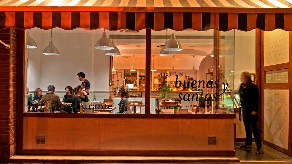 Fachada de Buenas y Santas de noche, con clientes cenando en el comedor